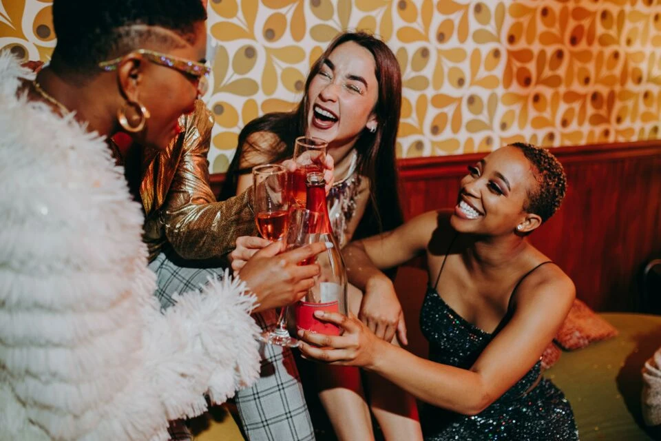 Four women laughing and toasting drinks (source : www.abcsalles.com)
