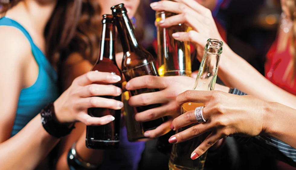 Young people toasting with beer bottles at a party